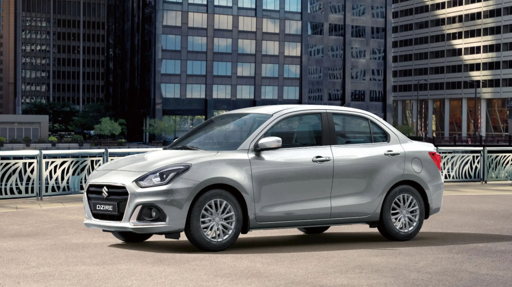 Auto sedán Suzuki Dzire plateado estacionado en la calle.  